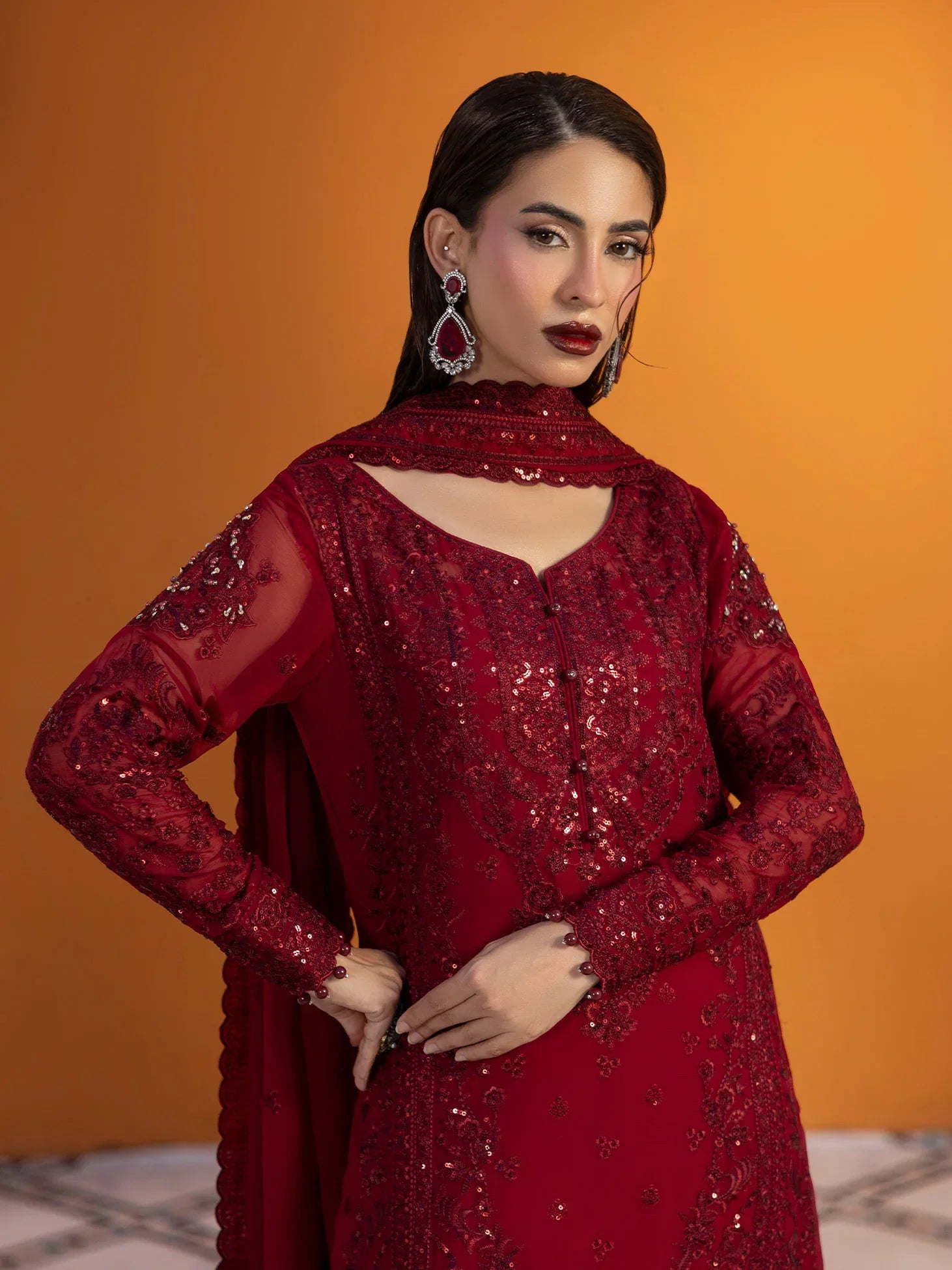 "Close-up detailing on the Gulaal Crimson shirt bodice, displaying fine gold tilla threadwork embroidery, shimmering sequin accents, and rich red fabric texture."