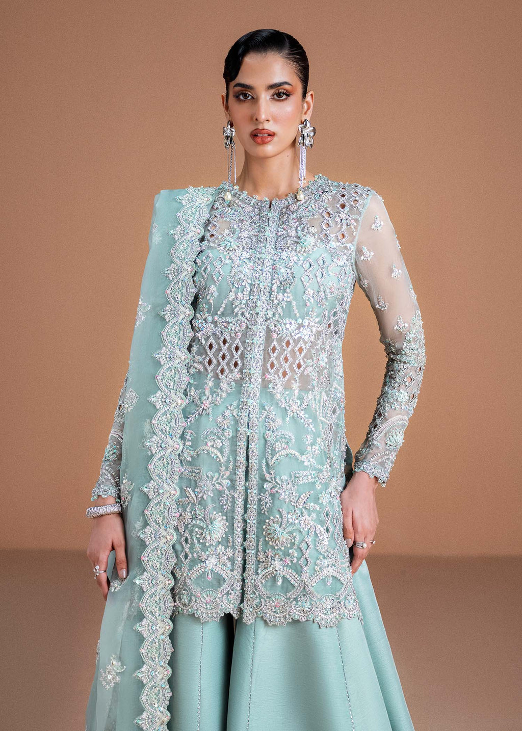 "Close-up premium craftsmanship on the Kanwal Malik Vania ice blue gown, highlighting the heavy crystal hand embellishments, delicate silver tilla motifs, and intricate shimmering embroidery details framing the front opening."