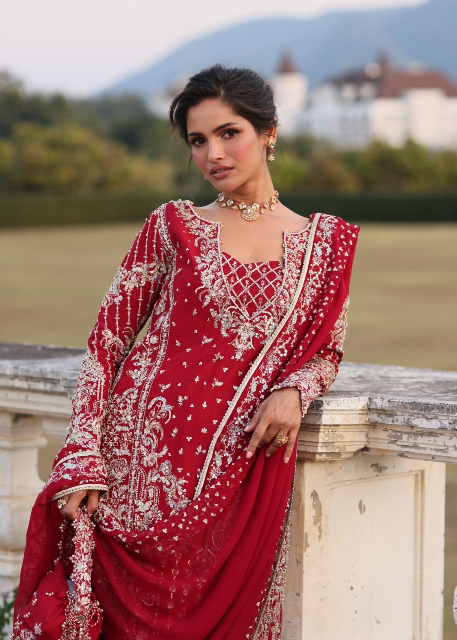 "Close-up premium craftsmanship on Kanwal Malik Aden magenta dress, highlighting the heavy traditional hand embellishments, sparkling crystal beadwork, and dense gold tilla layout on the neckline and front panels."