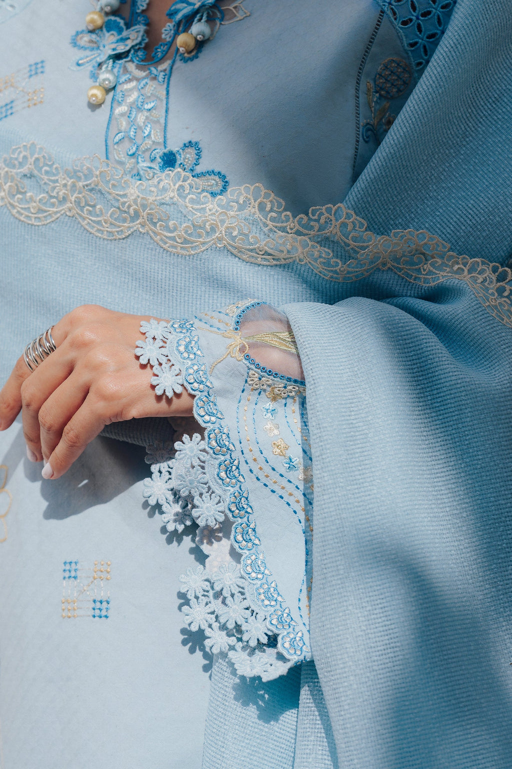 "Focus on the intricate sleeve cuff trimmings and lace hemline details of the Qalamkar QBP-05 MARTA stitched luxury suit, showing boutique-quality tailoring."